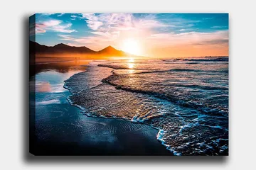 Lerretsbilde 70x100 cm - Solnedgang over en strand med milde bølger som ruller inn mot kysten - Blå / Oransje / Turkis - Innredning - Bilder & kunst - Lerretsbilder